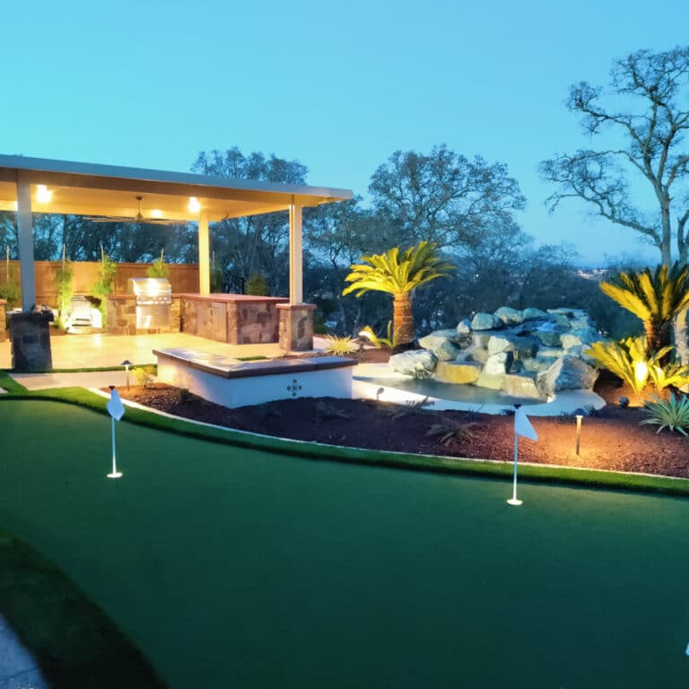 backyard landscaping with pergola, outdoor kitchen, and putting green