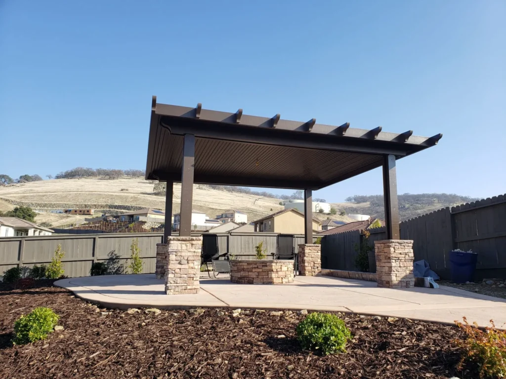 Backyard patio with brown pergola, stone fire pit, and new landscaping.